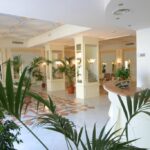 Vaaleasävyinen vastaanottoaula Hotel Villa Igeassa, aulassa useita palmuruukkuja