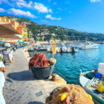 Kalastajien aluksia ja kahvilan pöytiä Ranskan Rivieralla Villefranche-sur-Merin rannalla