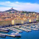 Marseillen Vieux Port-satama täynnä veneitä ja laivoja, taustalla kukkulalla Basilica Notre Dame de la Garde