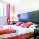 Parivuoteellinen standard-luokan huone Hotel de Suedessa, huoneessa kapea ikkuna ja pieni kirjoituspöytä