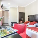 Hotel de Sueden kolmen hengen huoneessa parivuode ja yksi erillinen vuode sekä kirjoituspöytä