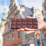 Nainen pitelee suklaalevyä Mustapäiden talon edessä.