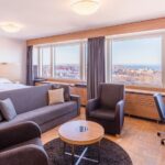 tilava huone jossa sohva, nojatuolit ja sängyt