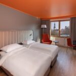 huone jossa erilliset sängyt, oranssit tuolit, ikkuna, puulattia