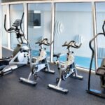 kuntosalilaitteita ikkunan edessä josta näkymä allasosastolle