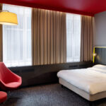 parivuode, kirjava kokolattiamatto, punainen nojatuli ja jakkata pöydän alla