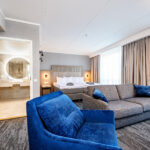 hotellihuone, jossa parivuode, sohva ja sininen nojauoli