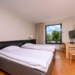 hotellihuone jossa erilliset vuoteet ja kirjoituspöytä