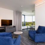 sviitin oleskelutila, jossa tv ja sininen sohva ja nojatuoli