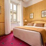 Hotellihuoneen sänky ruskealla päiväpeitteellä