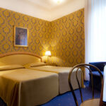 Hotellihuoneen sänky keltasella päiväpeitolla