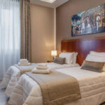 Hotellihuone erillisillä vuoteilla ja puisella sängynpäädyllä