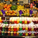 Värikkäitä hedelmiä ja smoothieita rivissä torikojulla.