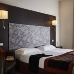 Hotellihuoneen vuode kukallisessa sängynpäädyllä