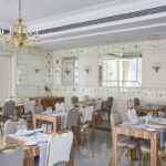 Ravintolasali, jossa puiset pöydät ja vaaleanharmaat tuolit