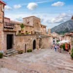 Vanhoja kivisiä rakennuksia, joiden välissä portaat, taustalla vuori.