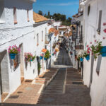 Kiviportaat rakennusten välissä, valkoisilla seinillä kukkaruukkuja