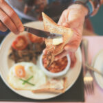 Aamiaiskattaus, kädet voitelevat leipää