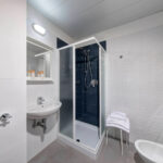 Kylpyhuone jossa suihkukoppi, lavuaari ja jakkara