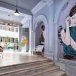 Käytävä jossa muraaleja ja värikkäitä tuoleja