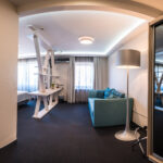 Hopeinen jalkalamppu sinisen sohvan vieressä