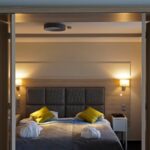 Parivuode jossa harmaa päiväpeitto ja keltaiset koristetyynyt