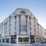 Vaalea hotellirakennus, jonka reunustalla puita ja autoja