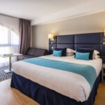 Hotellihuone jossa parivuode ja pieni sohva pöydällä