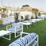 kattoterassi, jossa valkoisia pöytiä. tuoleja ja aurinkotuoleja