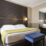 Hotellihuone, jossa tumma seinä ja parivuode jonka päällä vihreä päiväpeite