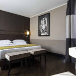 Hotelihuone jossa tumma seinä, parivuode ja taulu patsaasta seinällä