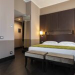 Hotellihuone, jossa näkyy kylpyamme ja parivuode vihreällä päiväpeitteellä