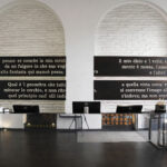 Hotellin vastaanotto, jossa seinällä italialaista tekstiä