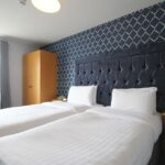 Hotellihuone, jossa kaksi erillistä vuodetta valkoisilla lakanoilla