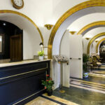 Holvikäytävä, jossa hotellin vastaanotto ja pöytäryhmiä tuoleineen