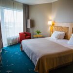 Hotellihuone, jossa parivuode ja punainen nojatuoli