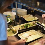 Nainen ottaa juustoa haarukalla hotellin aamupalalla